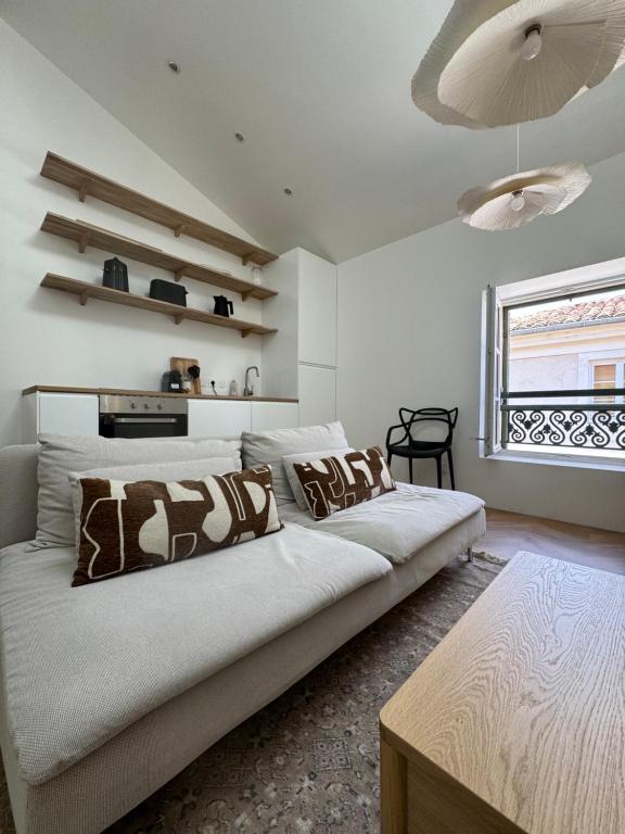 une chambre blanche avec un grand lit et une fenêtre dans l'établissement La Halte des Arènes de Nimes - Appartement Minimaliste - Ecusson Nimes, à Nîmes