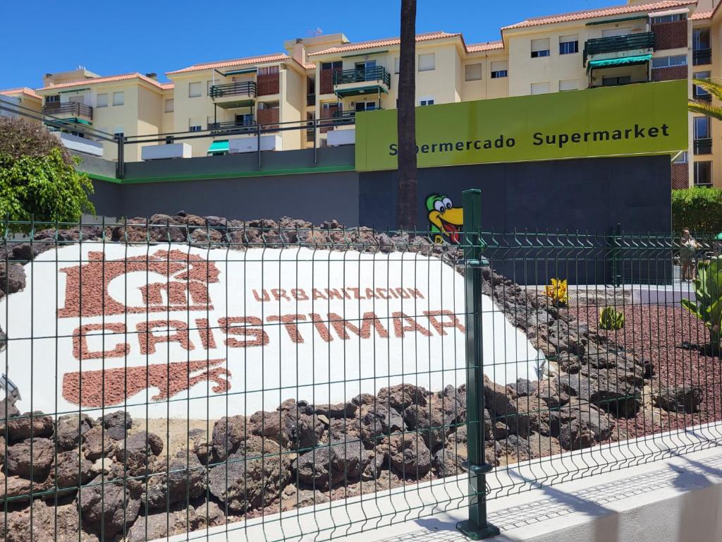 un uccello seduto su una recinzione di fronte a un edificio di Cristimar Roja Beach a Los Cristianos