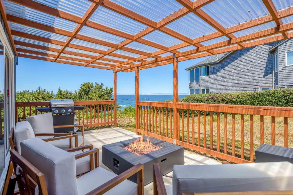 un patio con pérgola, mesa y sillas en Surfrider Beach House, en Depoe Bay
