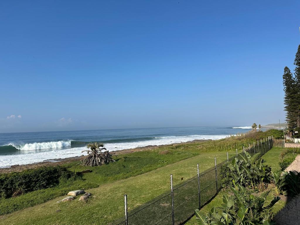 a beach with a fence and the ocean with waves at Summer Rocks 10 in Uvongo Beach
