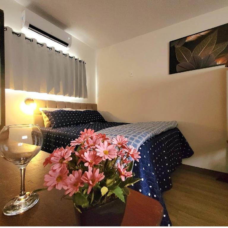 a bedroom with a bed and a table with a vase of flowers at Perfeito Studio 22 in Poços de Caldas
