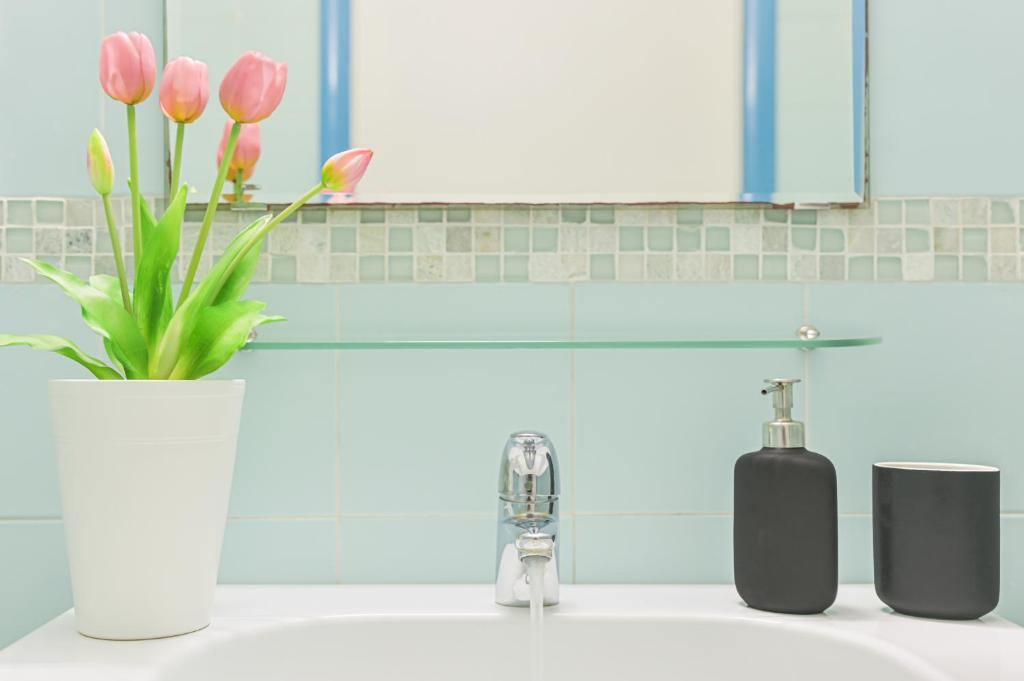 a bathroom sink with a vase of pink tulips at LINUS by BREATHE LIGURIA in La Spezia
