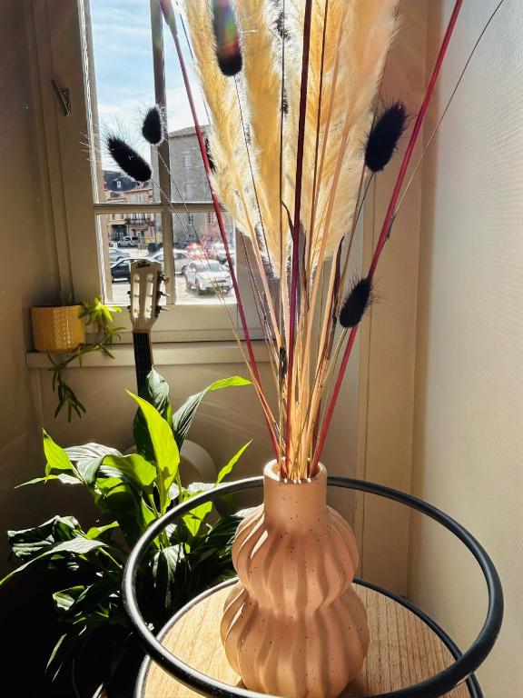 un vase avec des fleurs assis sur une table dans l'établissement Anastasia, à Villefranche-de-Rouergue