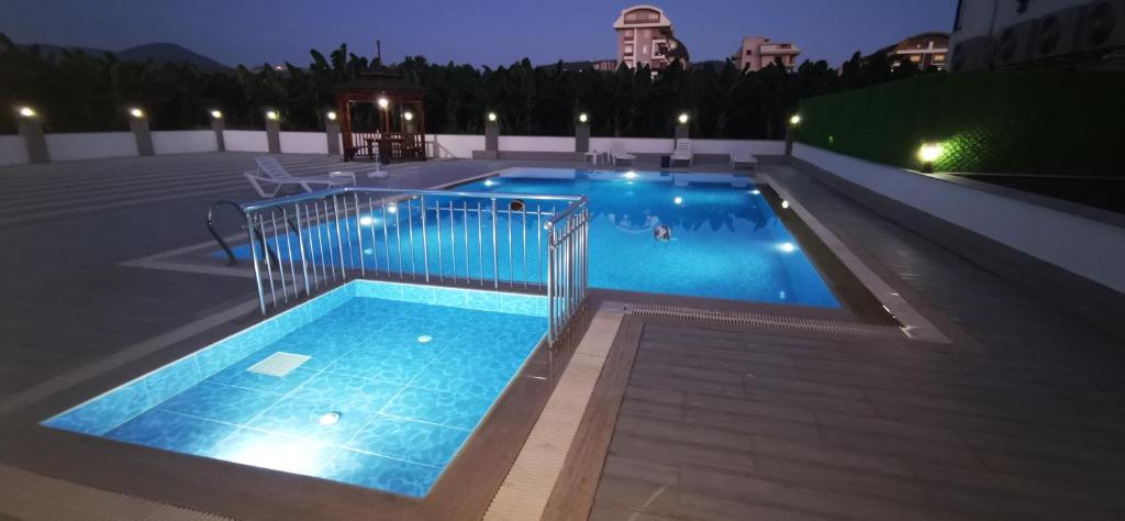a large swimming pool with blue water at night at Best life 6 in Alanya