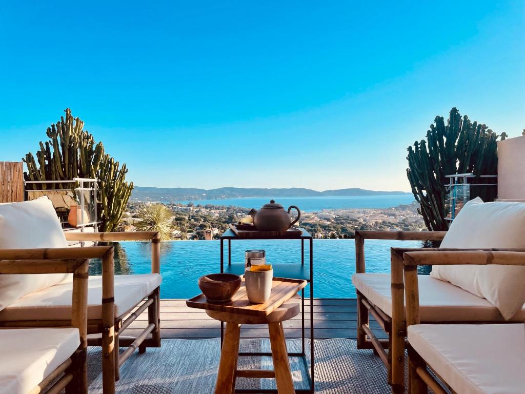 d'une terrasse avec des chaises et une vue sur l'eau. dans l'établissement Mas de charme 133m2 piscine chauffée vue mer panoramique, à Cavalaire-sur-Mer