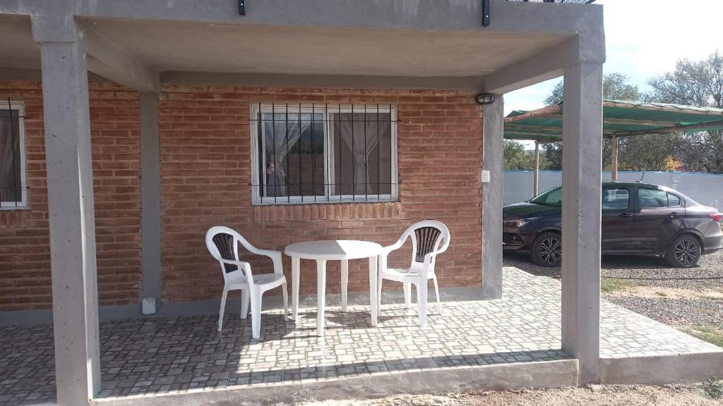 een patio met een tafel en 2 stoelen en een auto bij Complejo soñado in Mina Clavero