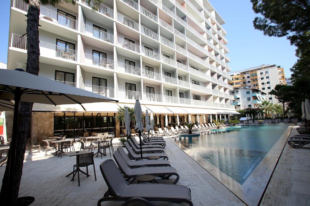 una piscina con sedie a sdraio e un edificio di Durres Bay Hotel a Durrës