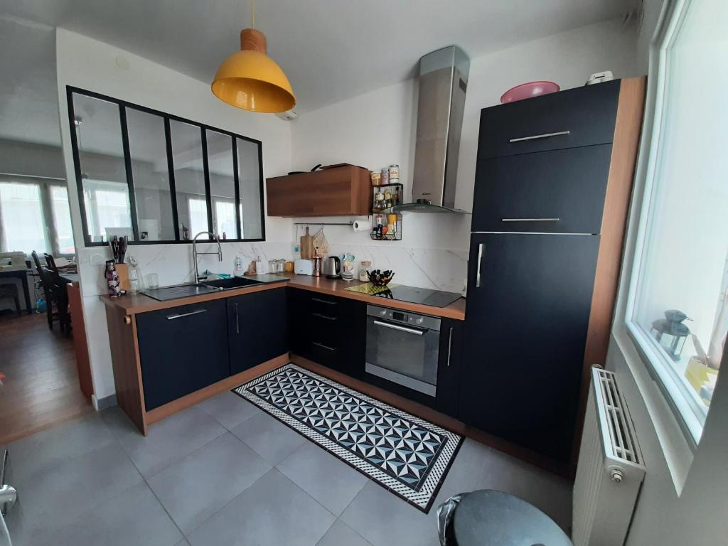 eine Küche mit einem schwarzen Kühlschrank und einem Küchenteppich in der Unterkunft chambre dans maison place du commando, bord de mer in Saint-Nazaire