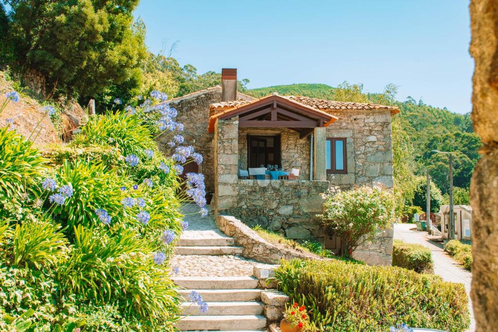 a stone house in a garden with flowers at Just Like Home - Quinta do Sinal 22 in Caminha
