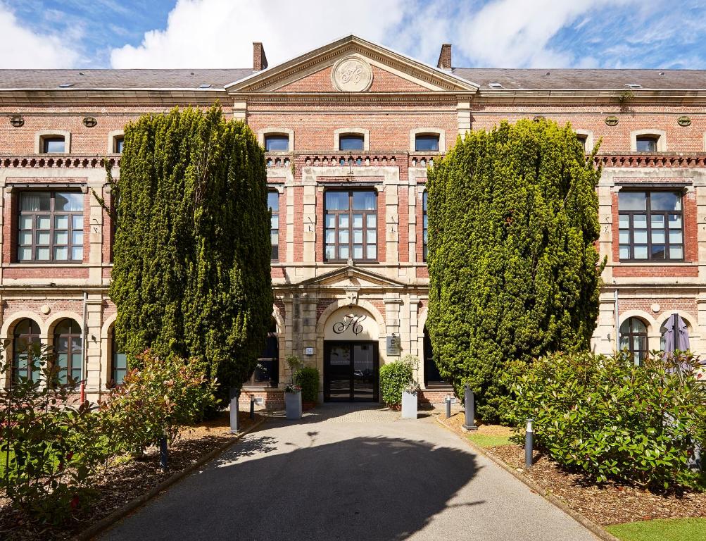 Un gran edificio de ladrillo con árboles delante. en Best Western Hôtel Hermitage, en Montreuil-sur-Mer