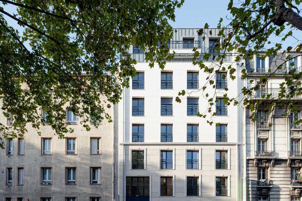 un immeuble d'appartements devant un arbre dans l'établissement Appartement 2 pièces 30min du centre de Paris, à Clichy