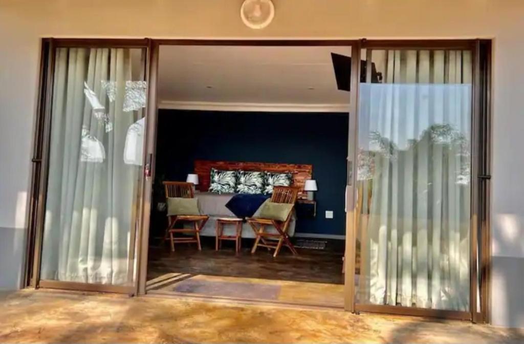 ein Wohnzimmer mit Glasschiebetüren und einem Tisch in der Unterkunft Verdiend En-suite Unit at Ngweni Private Game Farm in Hluhluwe