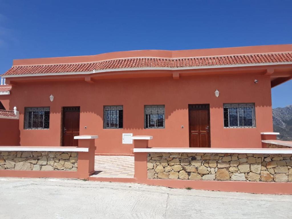 a red house with a stone wall at Coopérative Village Jbel Moussa du Tourisme in Rcham