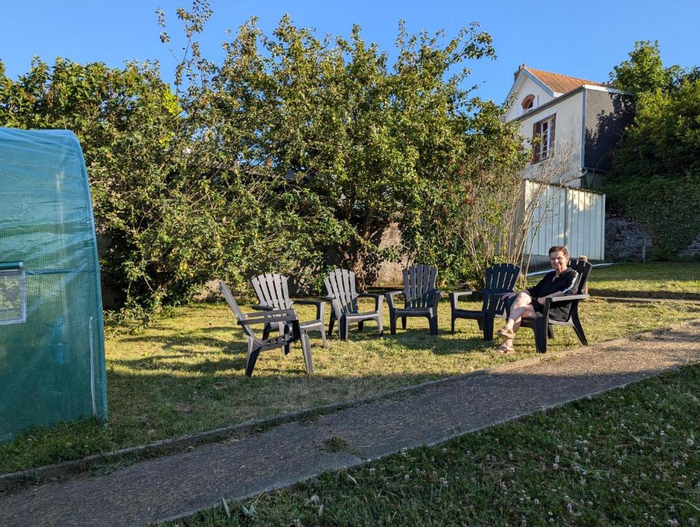un homme assis sur un banc à côté de quatre chaises dans l'établissement Le Jardin en centre ville - ANCV accepté, à Granville