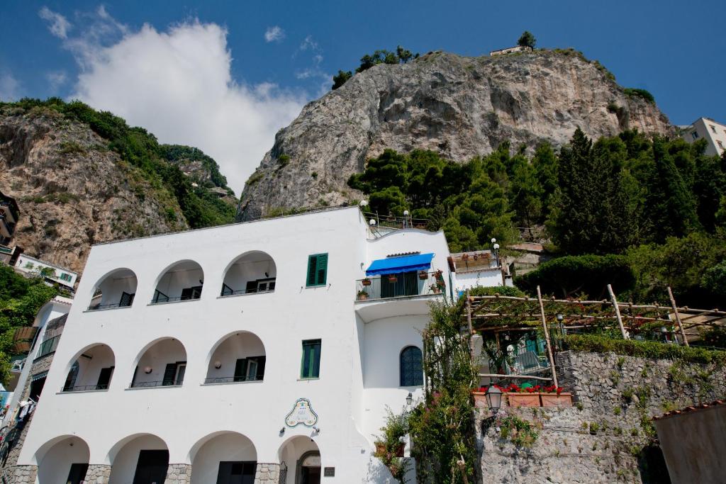 a white building in front of a mountain at Hotel Aurora in Amalfi