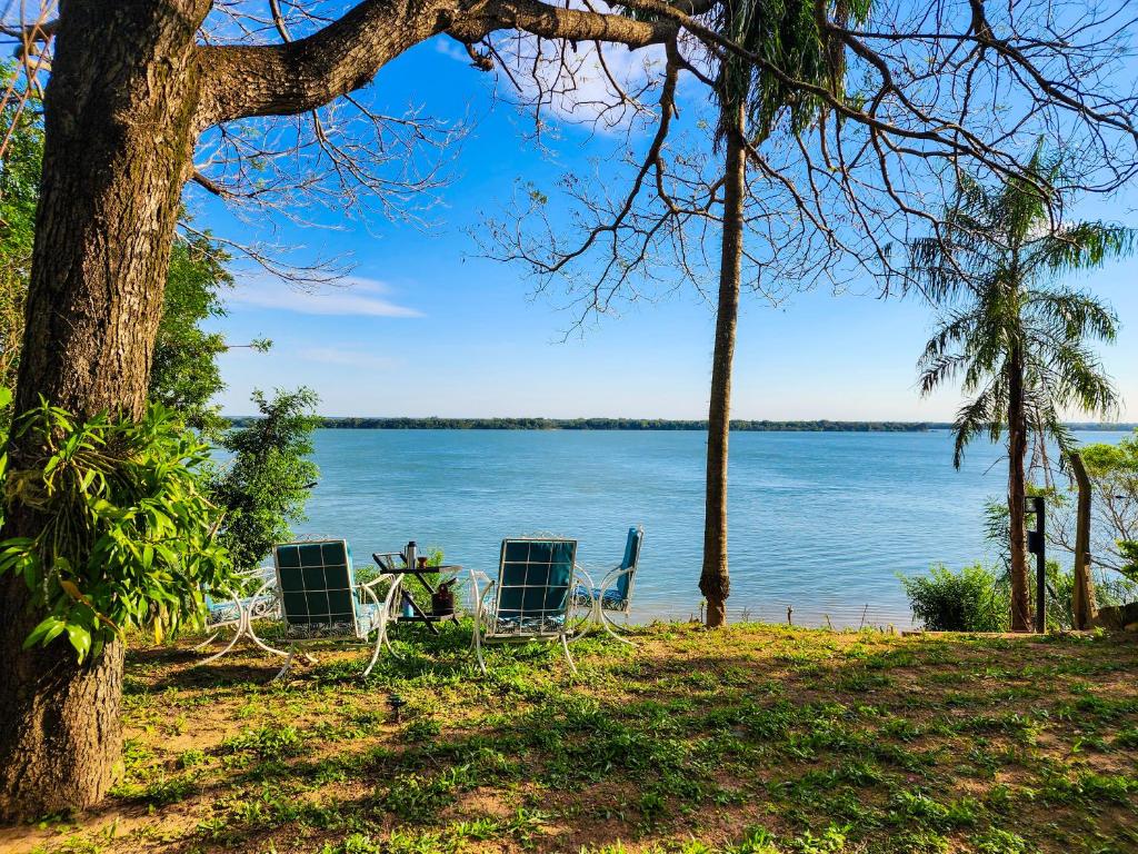 zwei Stühle und ein Tisch am Ufer eines Sees in der Unterkunft Casa frente al Río Paraná in Ituzaingó