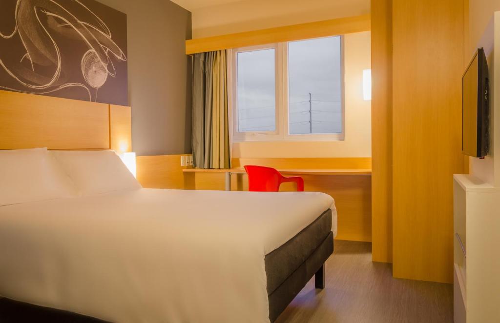 um quarto de hotel com uma cama e uma janela em Ibis Porto Alegre Assis Brasil em Porto Alegre