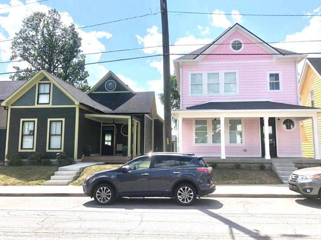 a black car parked in front of two houses at It's All Good - Two Homes Sleeps 18 in Indianapolis