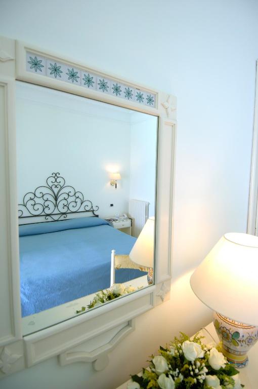 a mirror in a room with a bed and a lamp at Hotel Aurora in Amalfi