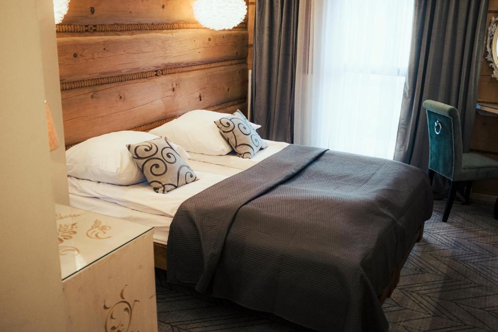 a bedroom with a bed and a chair and a window at Chałpa z bali in Zakopane