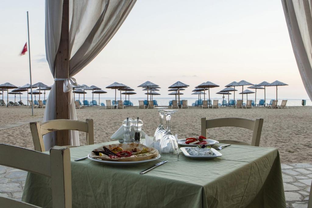 a table with food on the beach with umbrellas at Coral Blue Beach Hotel Gerakini in Gerakini