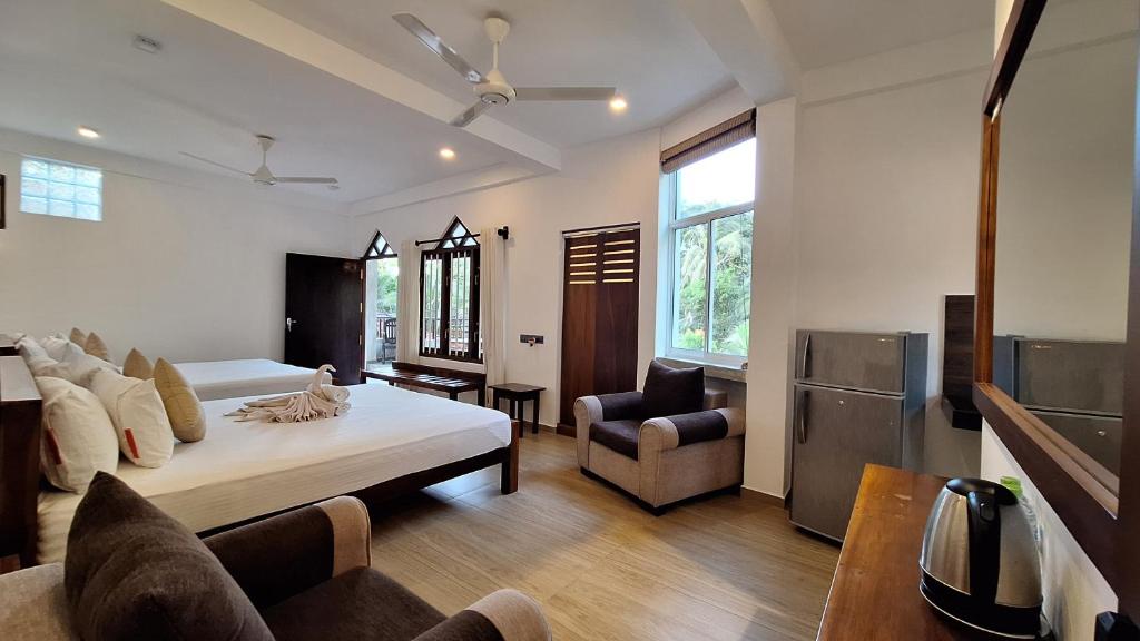 a bedroom with a bed and a couch and a chair at Villa Goodwill Paradise in Hikkaduwa