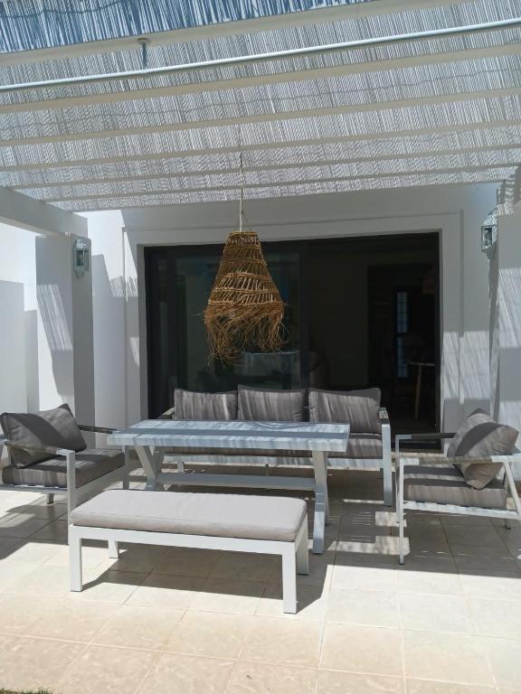 a patio with a table and a couch and a chandelier at El Rompido - Punta Coral in El Rompido