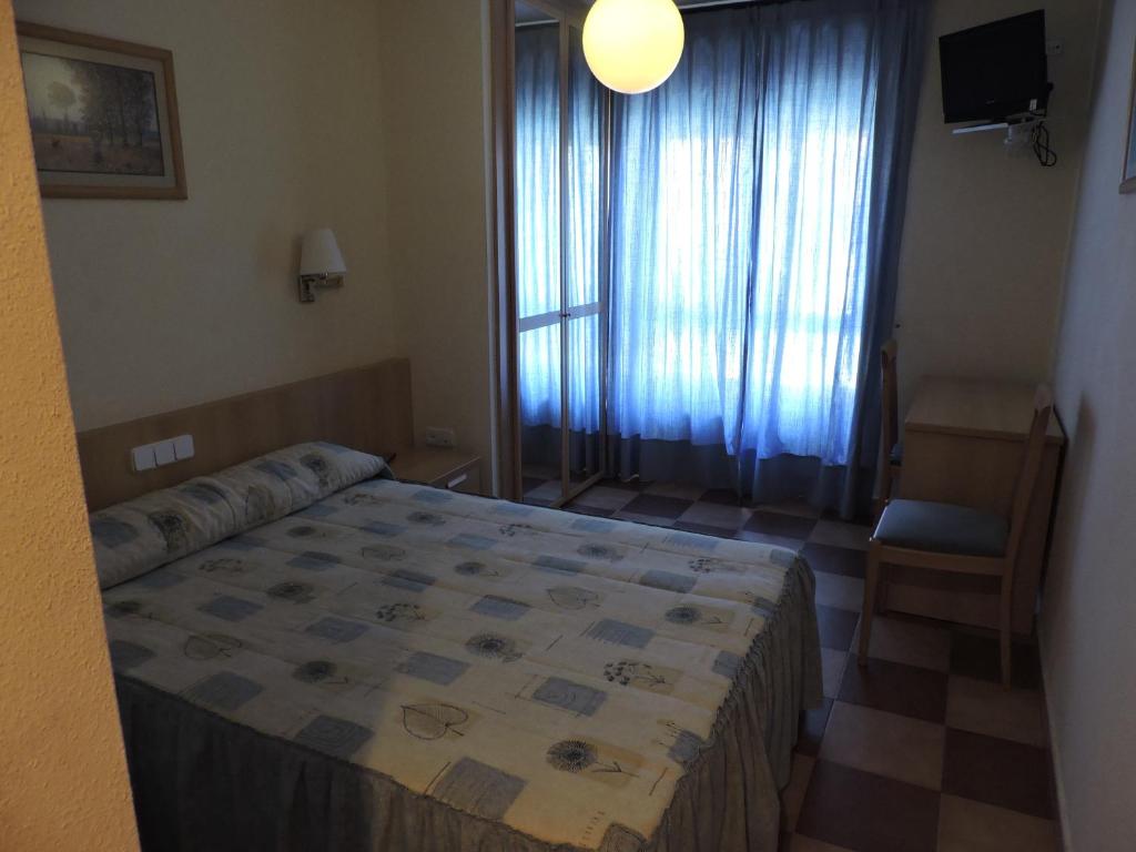 sypialnia z łóżkiem, krzesłem i oknem w obiekcie Mirasierra w mieście Bustarviejo