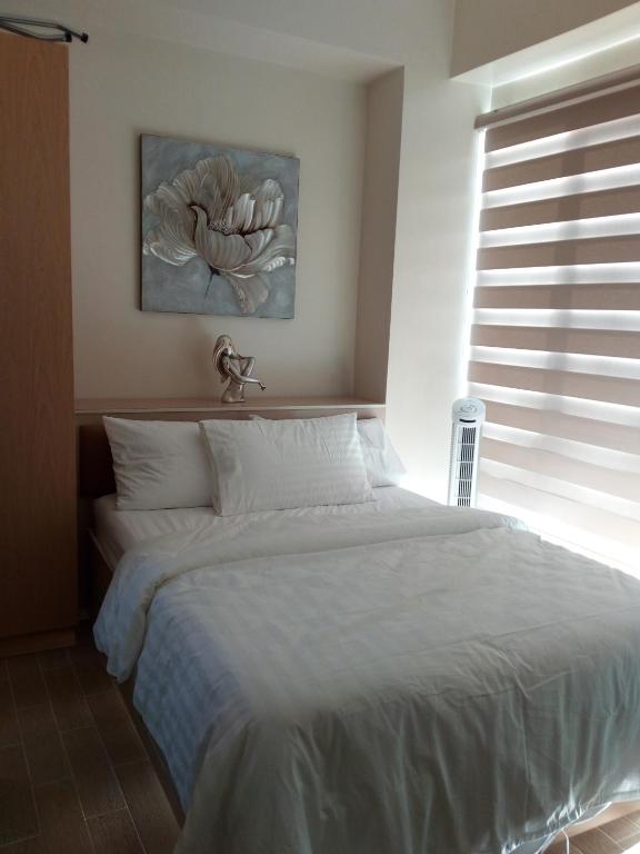a bedroom with a large white bed with a window at megaworld iloilo city, one madison luxury residences in Iloilo City