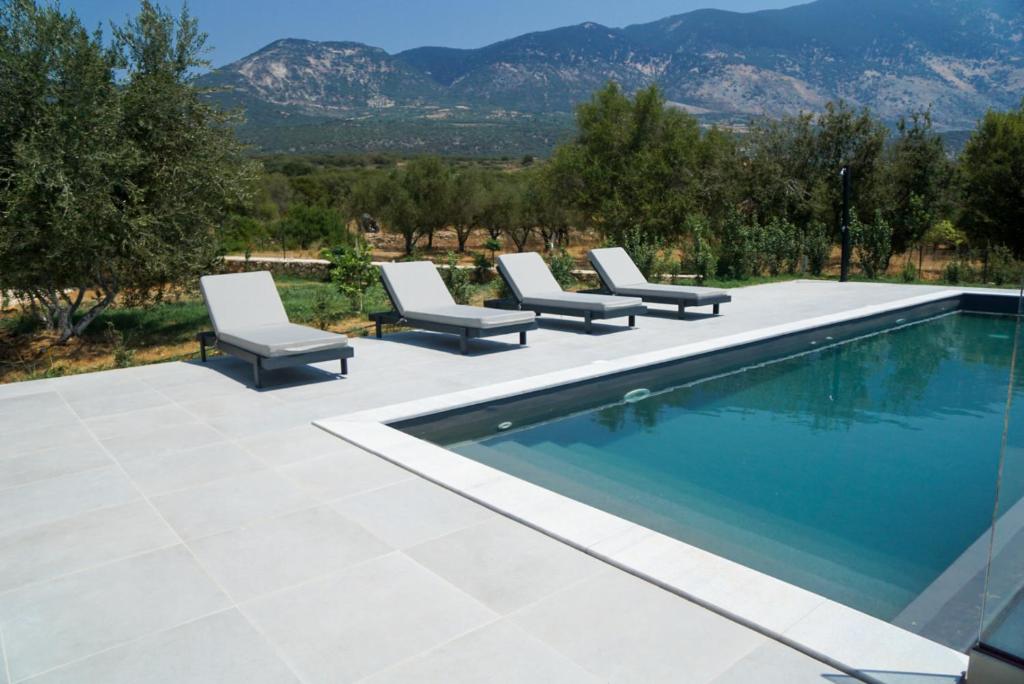 a pool with lounge chairs next to it with mountains at MENTOROS VILLAS in Karavadhos