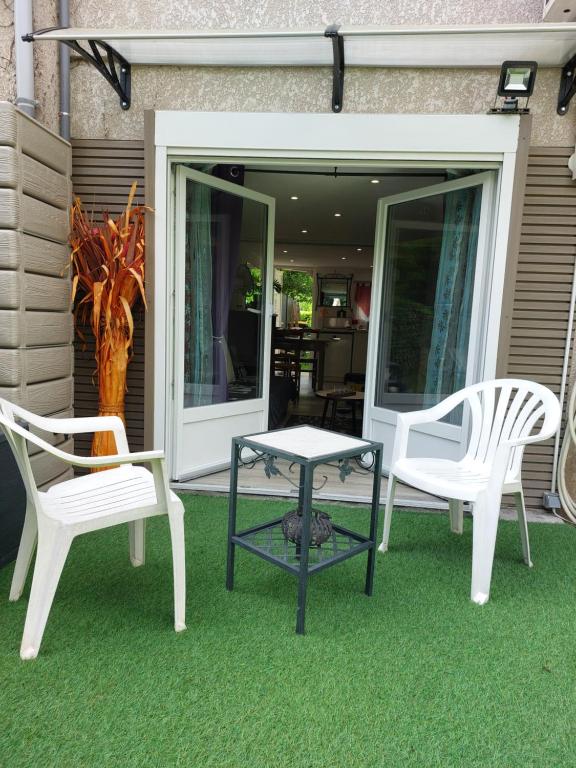 two white chairs and a table on a lawn at Douce Escale - Agen sud, T2, RDJ, clim réversible, proche ENAP in Agen
