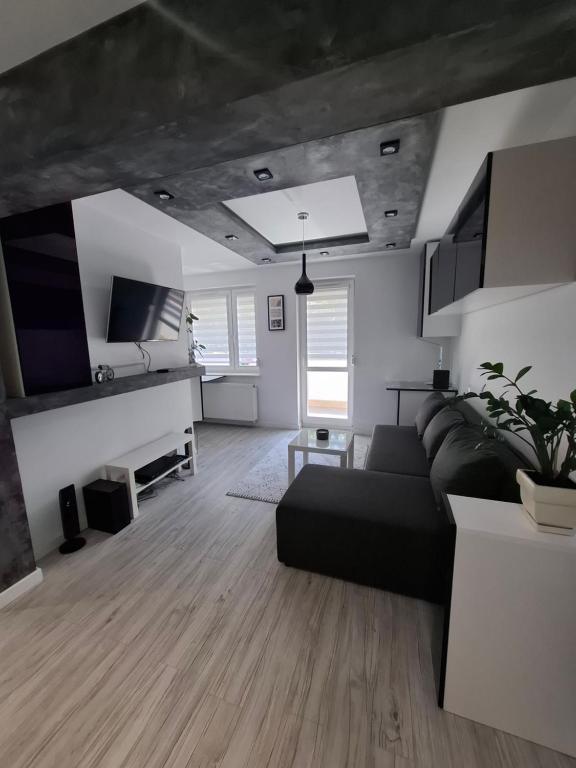 a living room with a black couch and wooden floors at Przytulny 2-pokojowy apartament na wakacje w Gdańsku in Gdańsk