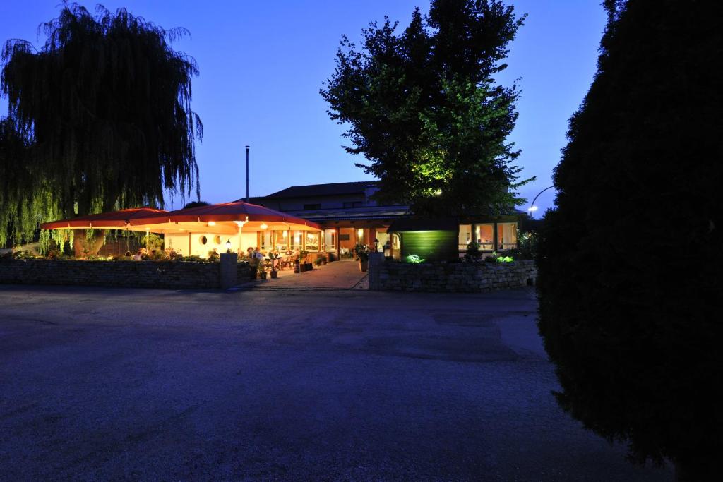 un edificio con mesas y sombrillas por la noche en Hotel Dreimädelhaus, en Espelkamp-Mittwald