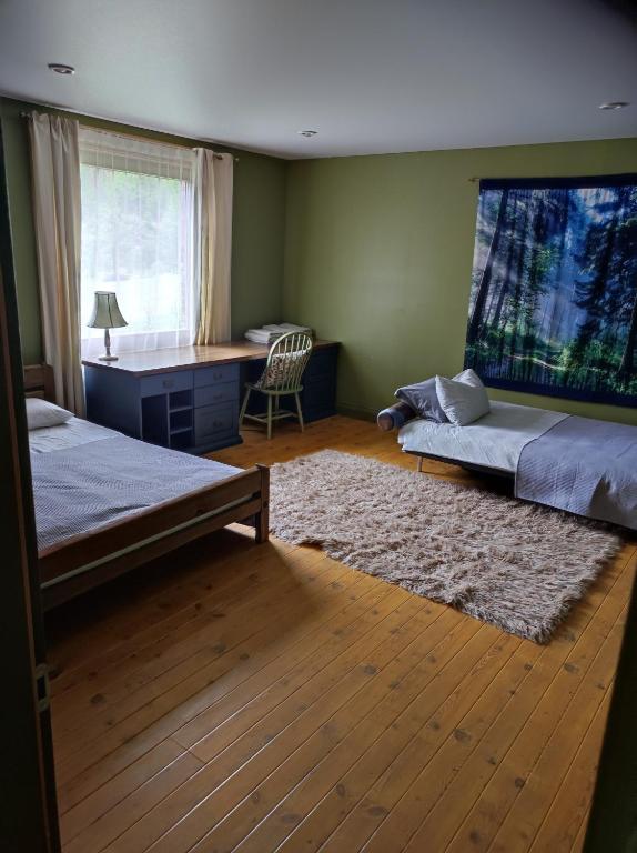 a bedroom with two beds and a desk and a rug at Forest apartment in the loop of the river Neris in Verkšonys