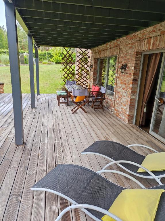 a wooden deck with chairs and a grill on it at Forest apartment in the loop of the river Neris in Verkšonys