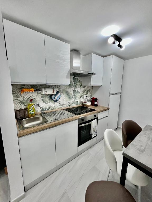 a kitchen with white cabinets and a table with chairs at A'MARE da Marco Loft in Sperlonga