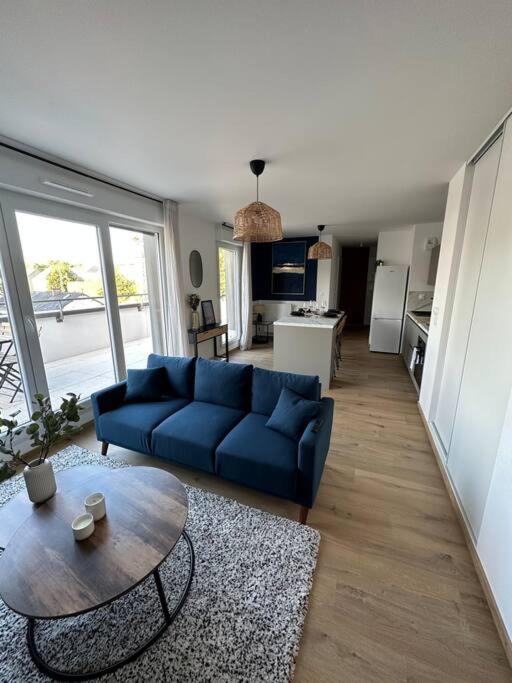 Una sala de estar con un sofá azul y una mesa. en Le Contrie - Bel appartement avec terrasse, en Nantes