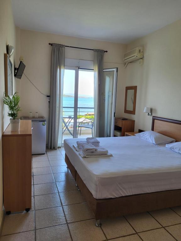 a bedroom with a bed and a view of the ocean at Vourvourou Hotel in Vourvourou