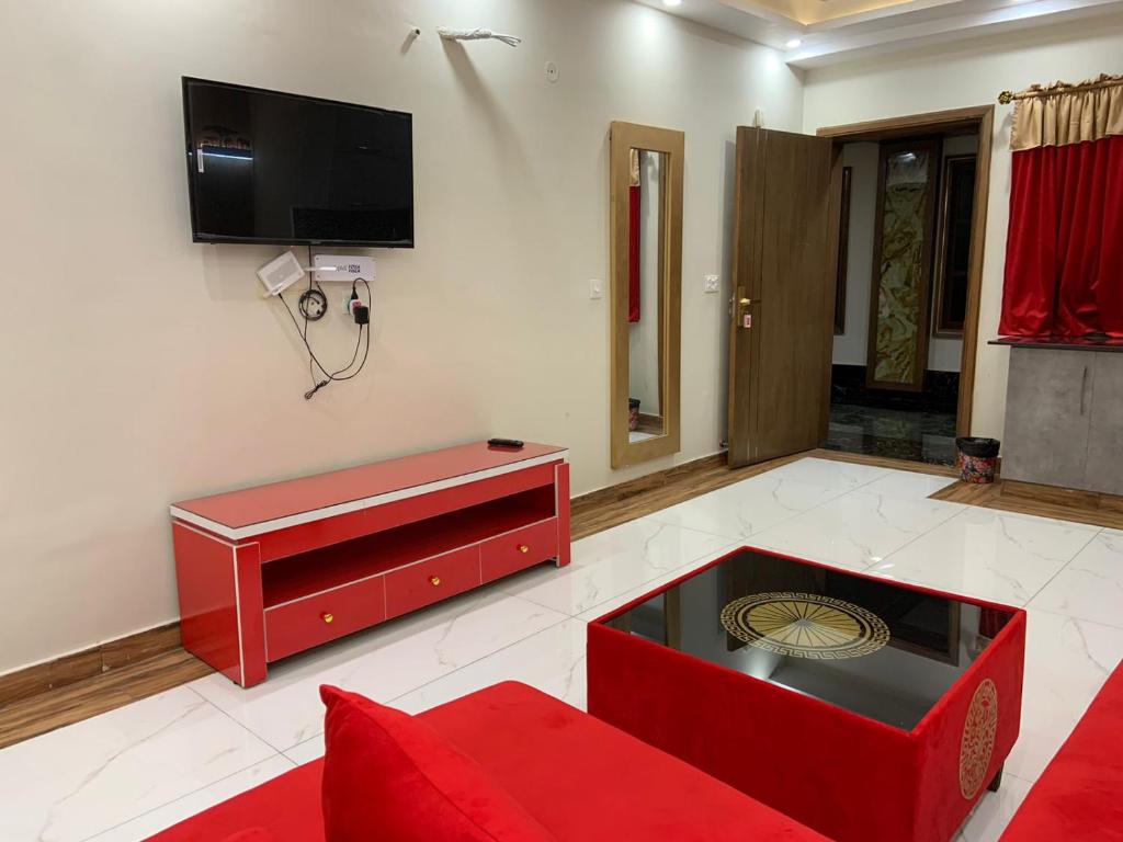 a living room with a red couch and a tv at Royal Galaxy Hotel & Residence - Near Islamabad International Airport & Motorway in Islamabad