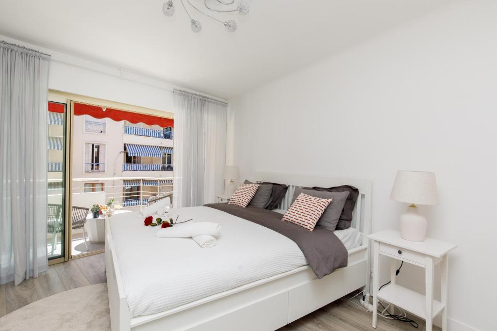 a white bedroom with a white bed and a window at T3Appartement de luxe Croisette en face de la plage Martinez 80m2 in Cannes