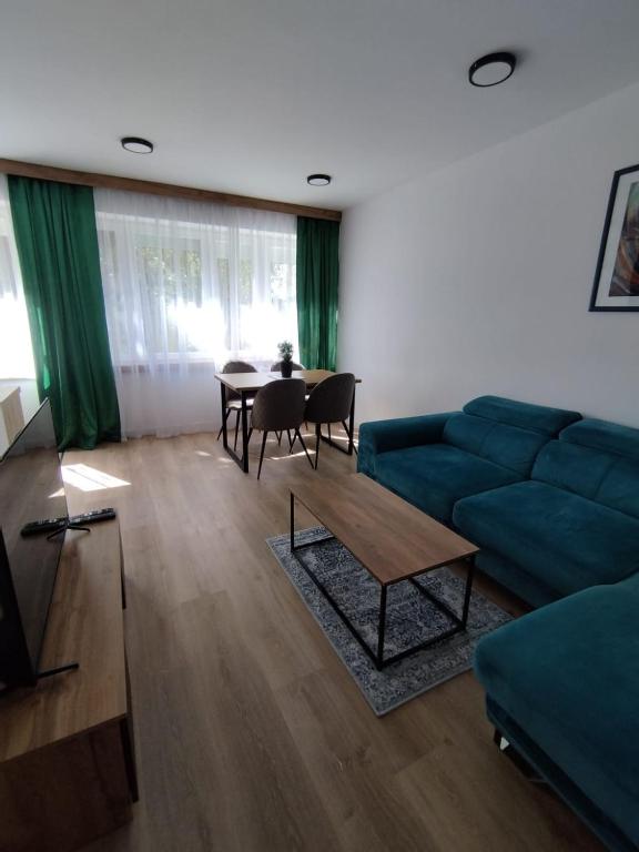 a living room with a blue couch and a table at Mieszkanie 11 Listopada in Konin