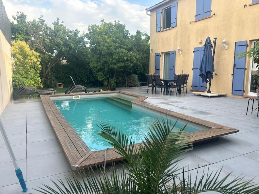 une piscine avec une terrasse en bois à côté d'une maison dans l'établissement Jolie maison provençale au volets bleu, à Marseille
