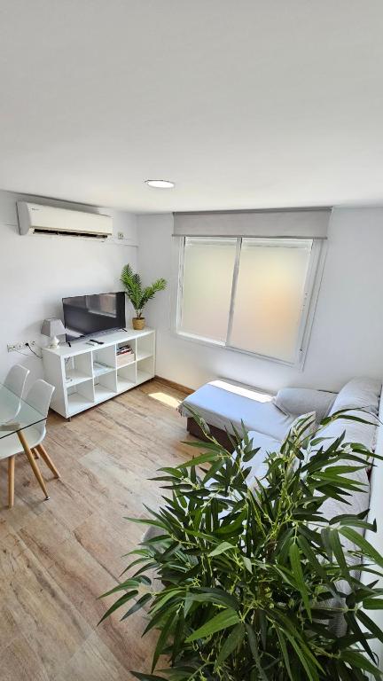 a living room with a couch and a tv and a table at Apartamento Los Mosaicos in Santiponce
