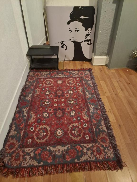 a red rug on the floor with a painting on the wall at London Smarty Rm in Thornton Heath
