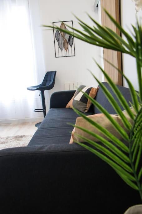 - un canapé noir dans un salon avec une plante dans l'établissement 2 pièces lumineux à 5 min à pied Stade de France, à Saint-Denis