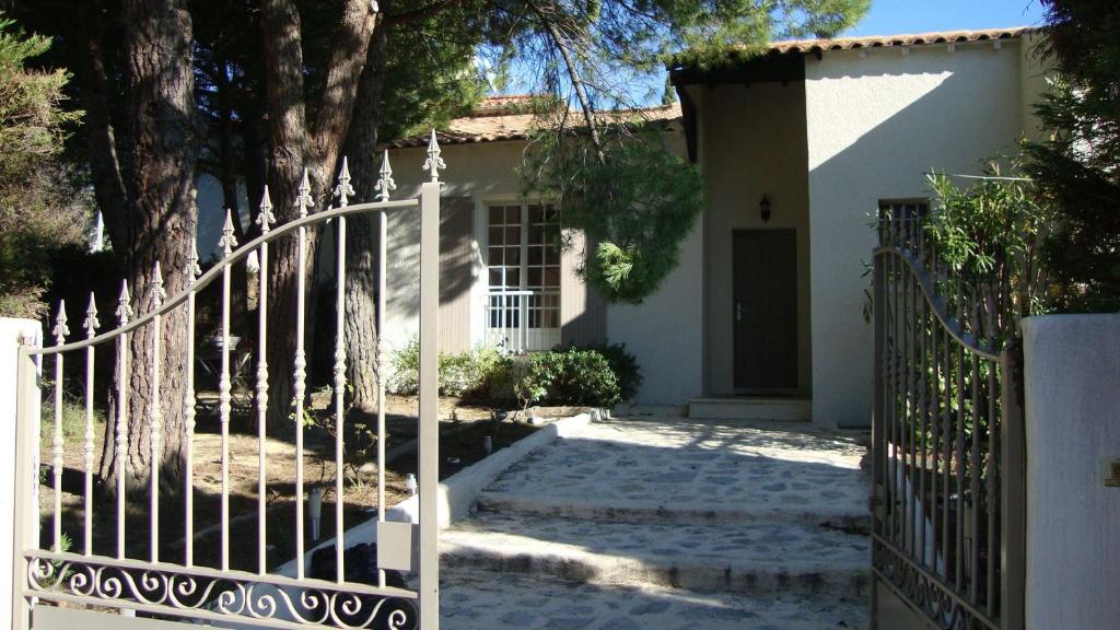 une maison blanche avec un portail et des arbres dans l'établissement La Fille du Berger, à Puissalicon
