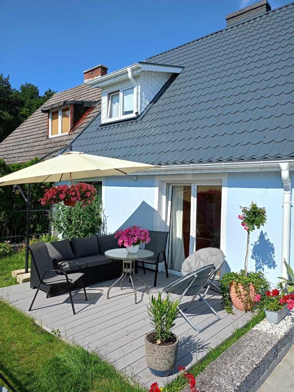 a patio with an umbrella and a table and chairs at Rybacki Domek 50 metrów do morza! in Dziwnów