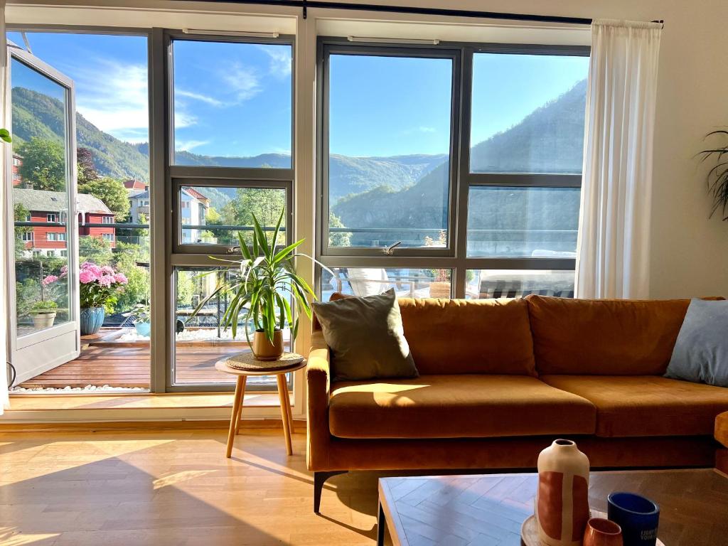 een woonkamer met een bank en een groot raam bij Top floor apartment with mountain view, terrace 22sqm, free parking in Bergen