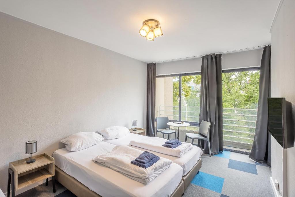 a bedroom with two beds and a large window at icke.apartments in Berlin