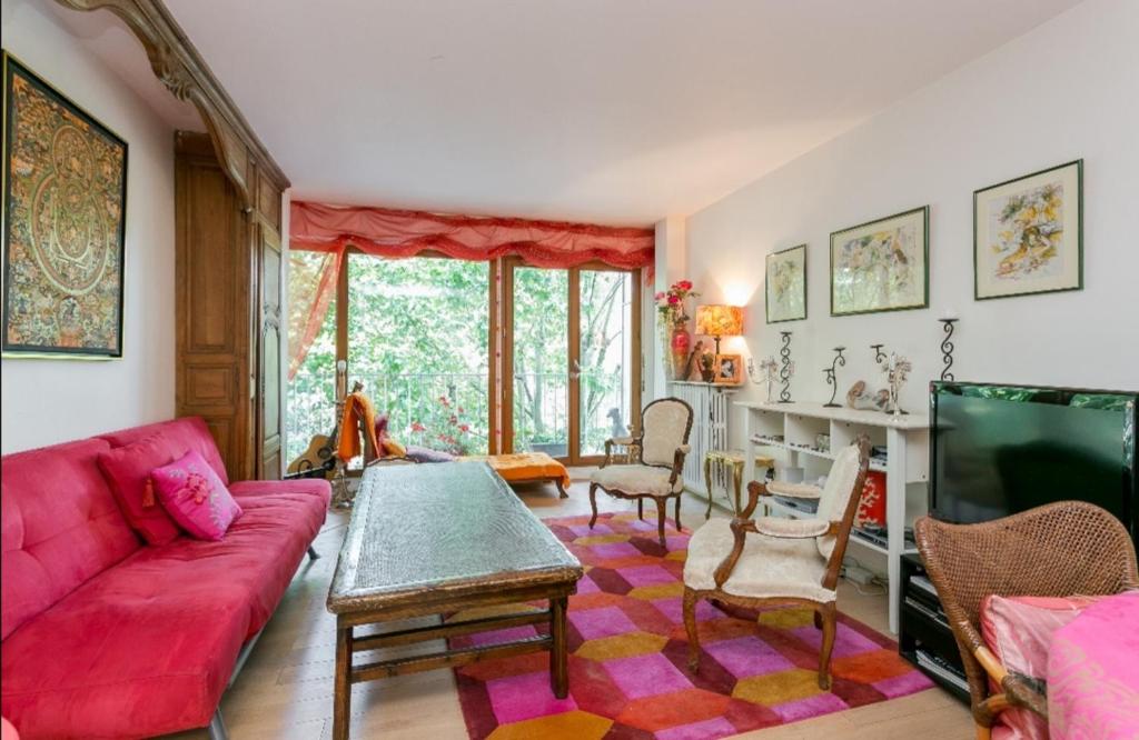 Una sala de estar con un sofá rojo y una mesa. en Lumineux 3 pièces face à la Seine à 100m du tramway T2, en Saint-Cloud